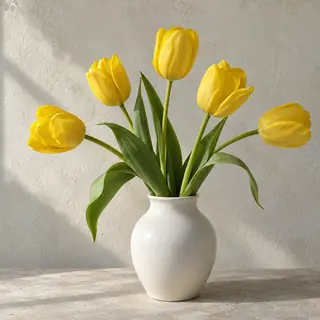 Fünf gelbe Tulpen mit langen Blättern in einer weißen Keramikvase vor einer Kalkwand